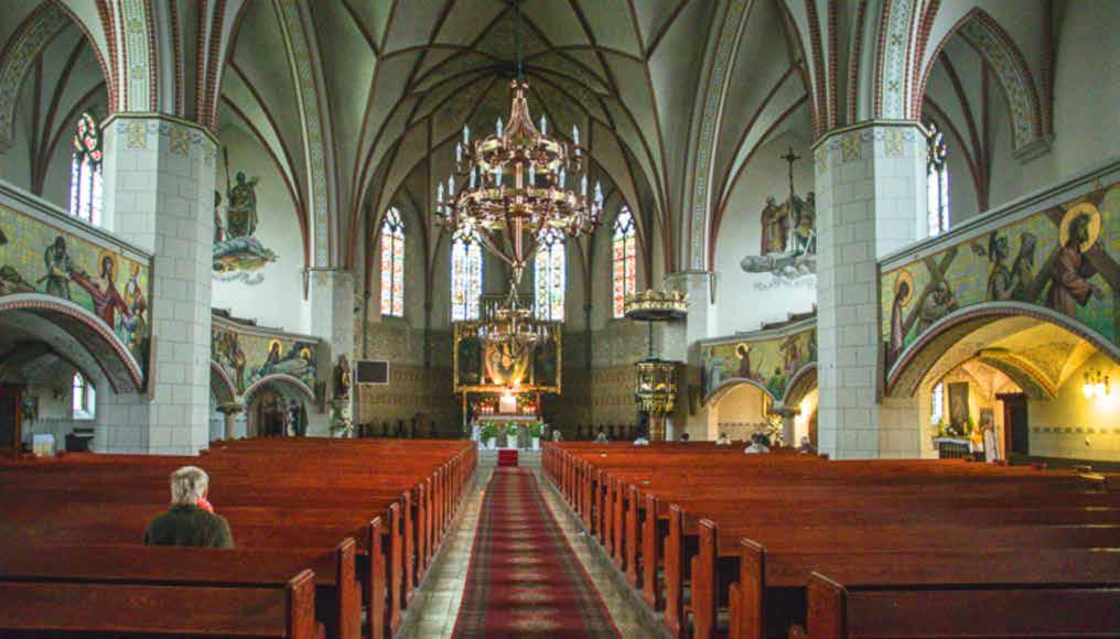 Interior view of the church featuring wooden pews and stained glass windows.