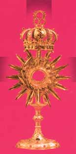 A golden monstrance with a crown on top, set against a pink background.