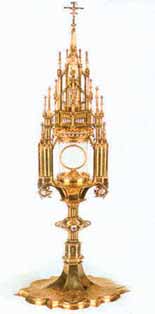 An ornate golden monstrance used for displaying the Eucharist, featuring intricate designs and a central circular holder.