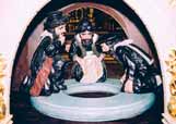 Three 18th-century sculptures depicting figures kneeling around a circular object, representing desecrators of the Hosts.