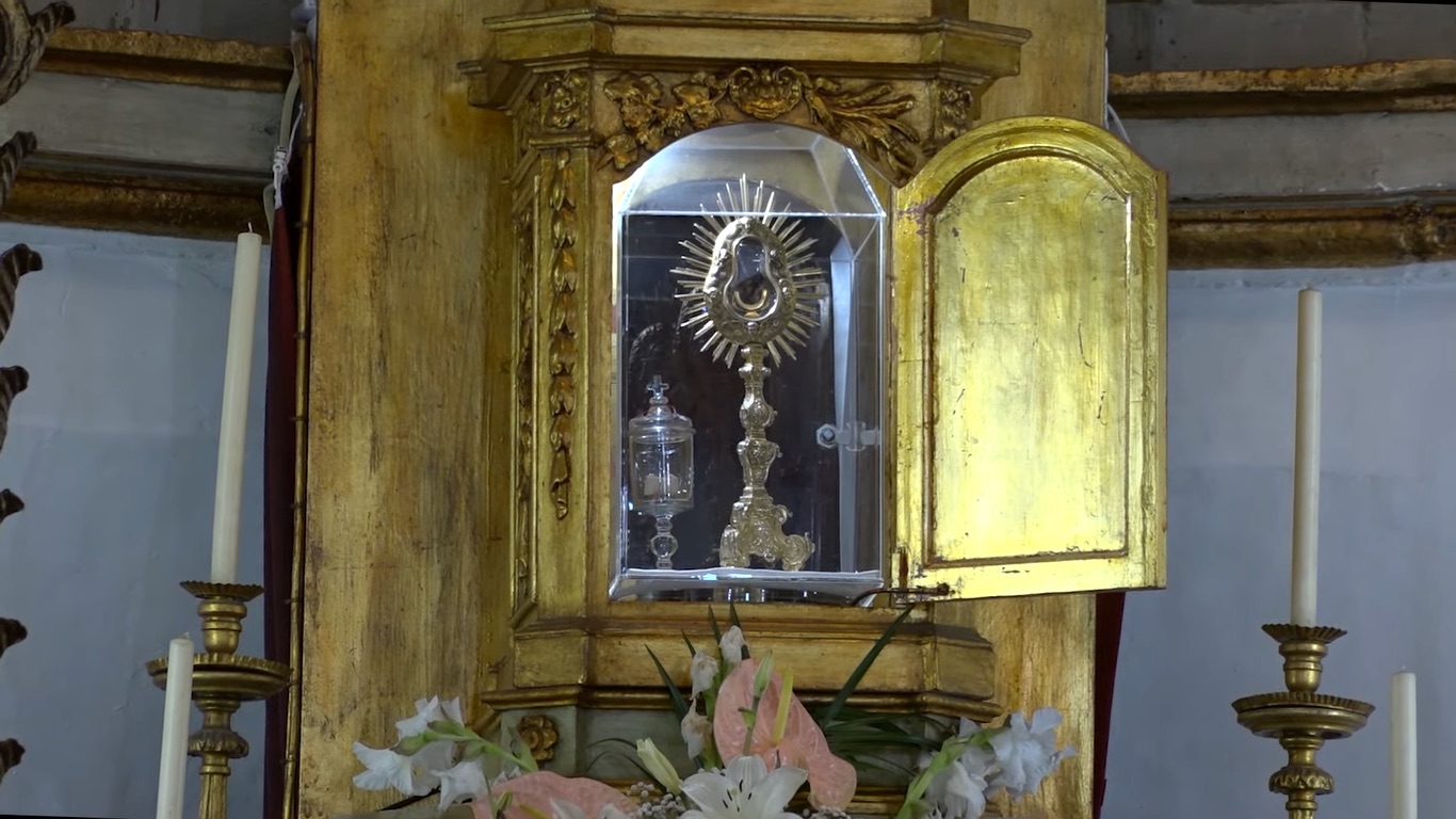 This image shows the preserved Host from the 1247 Santarém miracle, encased in a crystal vessel within a golden reliquary. The Host, which reportedly bled after being stolen, is displayed as a testament to the miraculous event, drawing pilgrims and receiving papal recognition over the centuries.