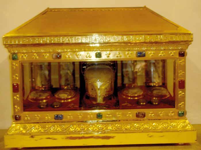 A golden reliquary with ornate decorations and embedded jewels, containing several glass containers.