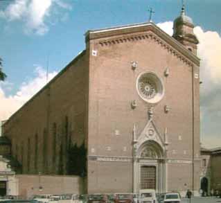 A large brick church with a rose window and a bell tower, under a partly cloudy sky.