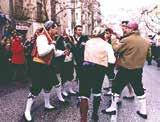 A group of people performing a traditional dance in festive attire during a procession.