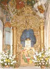 An ornate altar with a golden frame and flowers, likely in a church setting.