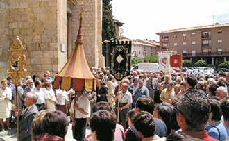 A crowd participating in a religious procession with banners and a canopy.