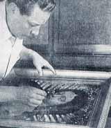 A man restoring or examining a framed image of the Virgin of Guadalupe.