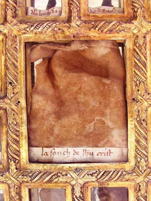 A close-up of a relic encased in ornate framing, showing a piece of cloth.
