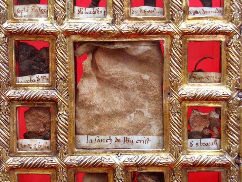 An ornate frame containing relics with a prominent piece of cloth in the center.