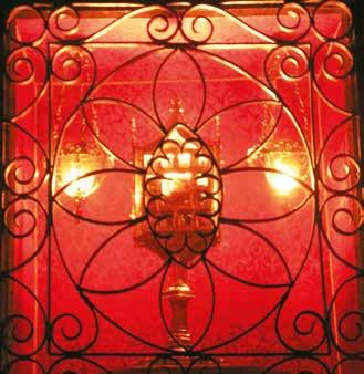 A decorative wrought iron screen enclosing a golden monstrance with lights behind it.