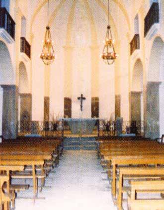 Interior view of a church sanctuary with wooden benches and a cross at the altar.