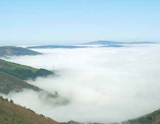 Panoramic view of O'Cebreiro, the site of the Eucharistic miracle, with misty hills symbolizing the mystical event.