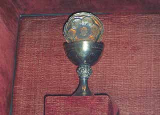 A chalice displayed against a red background, possibly containing a relic or sacred object.