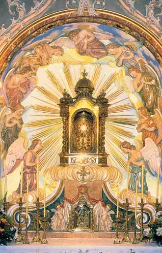 A golden monstrance surrounded by angels, radiating light in a church setting.