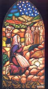A stained glass window depicting a woman praying with figures in a landscape.