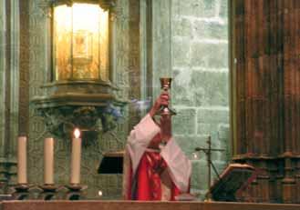 A priest holding a chalice during a religious ceremony in a church setting.